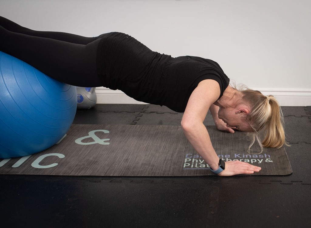 Caroline in a plank position with her legs resting on a blue exercise ball