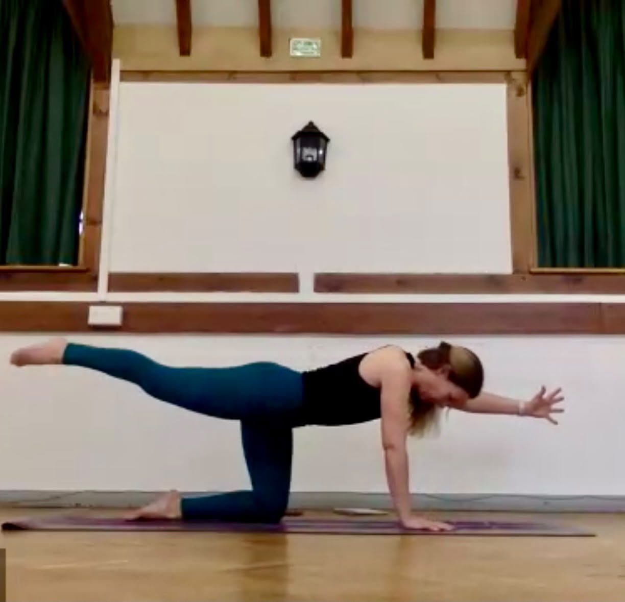 Khem demonstrating a kneeling balance pose with one leg and the opposite arm extended